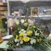 Mix of yellow, white and blue blooms adorning a handmade cross. 