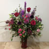 This lush and dramatic floral arrangement  in an elegant, dark pink