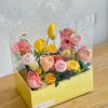 A yellow rectangular box filled with coral, pink, white, and yellow flowers.