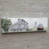 Displayed is a scene of a weathered, gray barn with a blue