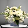 A dreamy white arrangement of hydrangea, roses, and other seasonal flowers arranged