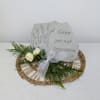 Memorial stone sitting on easel, with artificial decor and a ribbon.

&quot;Gone yet