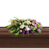 A beautiful and elegant casket spray featuring a mix of pink roses