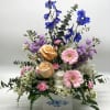 A soft pastel blend of fresh flowers designed in a white wooden