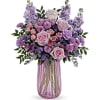 PURPLE, LAVENDER, PINK, AND CREME ROSES IN A TALL, CLEAR/PINK VASE