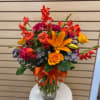 Mixed cut arrangement with red glades, orange lilies, circus rose, lavender accent