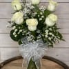 6 White roses with filler flowers arranged in vase. The white rose
