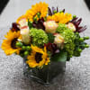 A whimsical grouping of fun flowers including sunflowers, hydrangea, roses, berries and