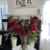 Dozen Lush Red Roses with a mix of Eucalyptus in a vase.