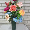 A green cone arranged with artificial anemones, peonies, roses, hydrangea, and mixed