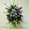 This Standing Spray Includes Lavender Gladiolas, Bells of Ireland, Blue Delphinium, Purple