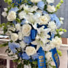 A graceful white and blue sympathy spray adorned with elegant white lilies