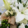 A lush mix of white flowers arranged in neutral cube container. 