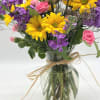 A bright combination of yellow daisies, purple stock, peach roses and pink
