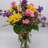 A bright combination of yellow daisies, purple stock, peach roses and pink