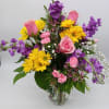 A bright combination of yellow daisies, purple stock, peach roses and pink