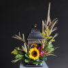 An artistic black lantern adorned with beautiful fall flowers that will bring