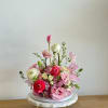 A flower arrangement in the shape of a cake, with pink, light