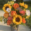 A fall arrangement bursting with sunflowers and roses interspersed with other locally