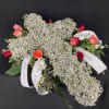 A large cross covered in Baby&#039;s Breath sits on a bed of