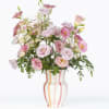 Full arrangement filled with local lisianthus and eucalyptus in a ceramic striped