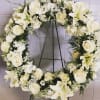 Roses, lilies, and white flowers in a circular wreath, unending and compassionate.