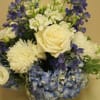in a beautiful ceramic Delftware-like pottery sit hydrangeas, roses, and delphinium
