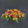 A mix of seasonal flowers in shades of reds, oranges, yellows centered