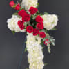 A cross form covered in white hydrangeas or carnations with a rose