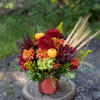 A cinnamon-gold cylinder vase adorned with festive pumpkins and natural dried wheat.