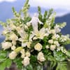 A serene and elegant floral arrangement featuring white lilies, roses, and snapdragons