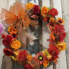 Silk Seasonal flowers mixed with greens and leaves on a grapevine wreath.