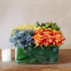 Low square arrangement of artfully arranged roses, pin cushions, thistle, billy balls