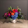 White cylinder container with blue hydrangea, roses, spray roses, stock, thistle and