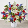 A collection of red roses, blooming white lilies, and blue delphinium come