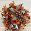 A sunflower and leaf wreath with berry and greenery accents. 
