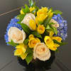 A radiant mix of soft ivory roses, cheerful yellow daffodils, and delicate