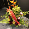 All tropical arrangement with cymbidium orchids, anthuriums and proteas, accented with greenery.