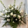 White roses, stock, larkspur, and cushion mums nestled within greenery in a