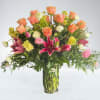 A vibrant mix of coral roses, stargazer lilies, and delicate blooms arranged