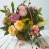 This charming basket arrangement combines soft pastels with vibrant greens, creating a