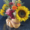 An adorable pumpkin container full with fall flowers.