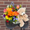 Bright blooms arrive in a basket with a little fuzzy friend! Bear