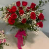 a dozen red roses in a vase with babies breath and greens