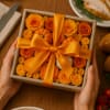 A warm embrace of golden- orange roses accented with petite pumpkins captures