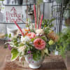 Variety of blooms and interesting textures in a white ceramic vase.
