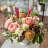 Variety of blooms and interesting textures in a white ceramic vase.