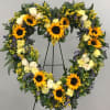 This heart-shaped standing wreath offers a warm and uplifting tribute with golden