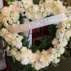 This all-white heart-shaped wreath features creamy roses, chrysanthemums, hydrangea, and delicate greenery