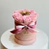 Soft preserved pink roses surround a single radiant gold rose at the